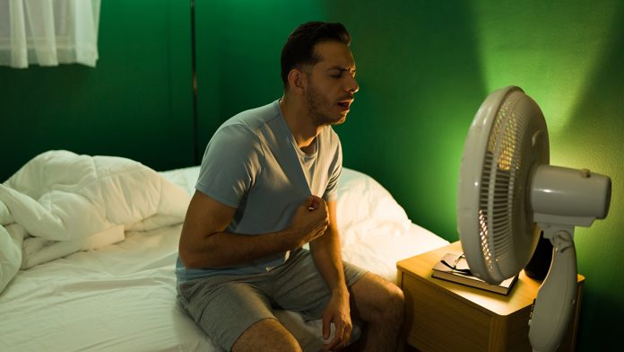 Hispanic man turning on the fan at night